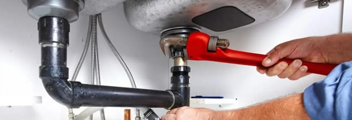 Garbage disposal repair technician tightening the sink drain and disposal connection in Providence, RI