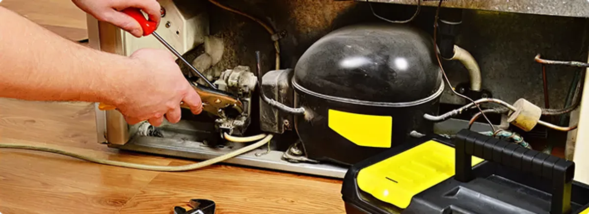 Refrigerator repair technician fixing the compressor and wiring in Providence, RI